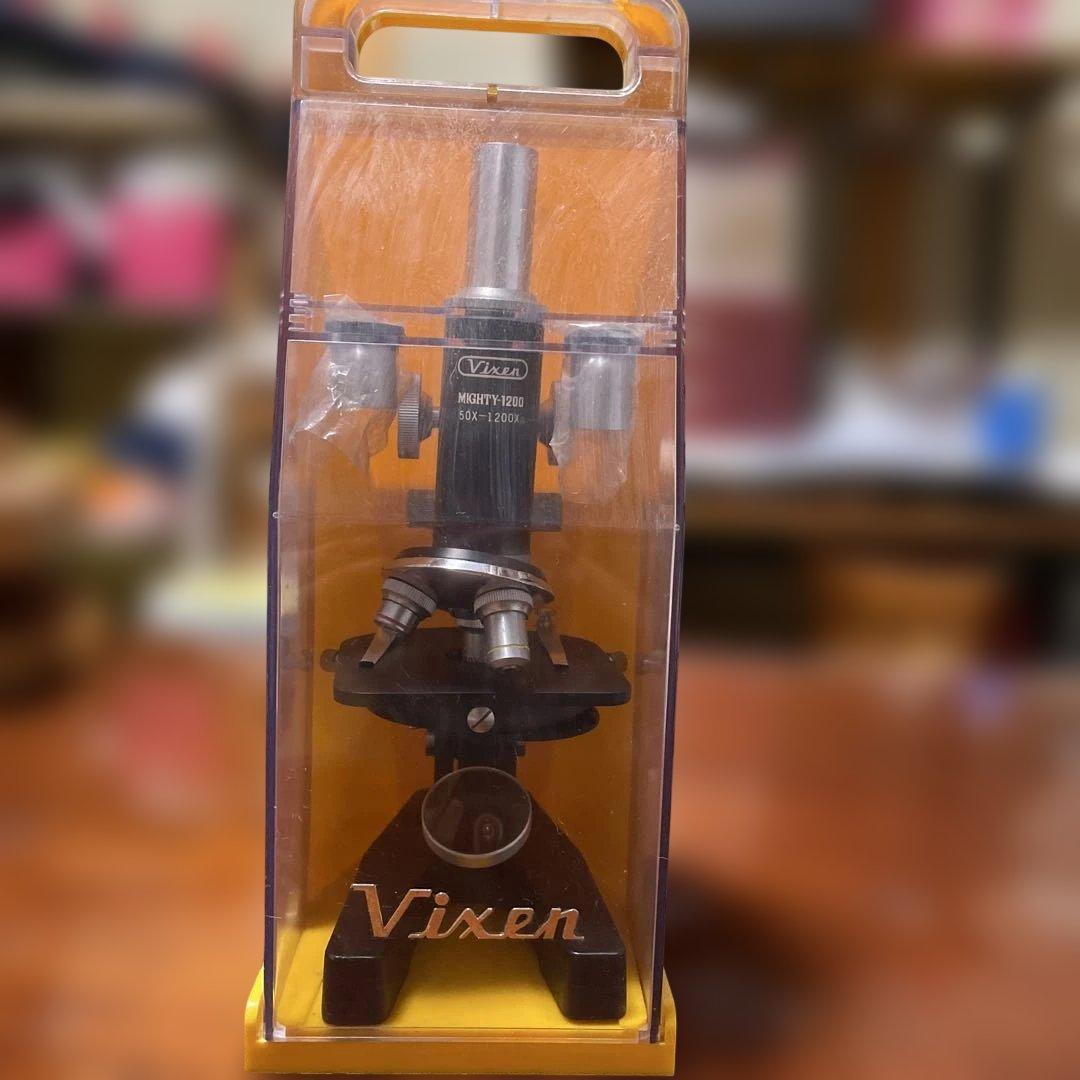 Vixen MIGHTY-1200 microscope (50X–1200X) shown inside a clear plastic carrying case with the Vixen logo visible.