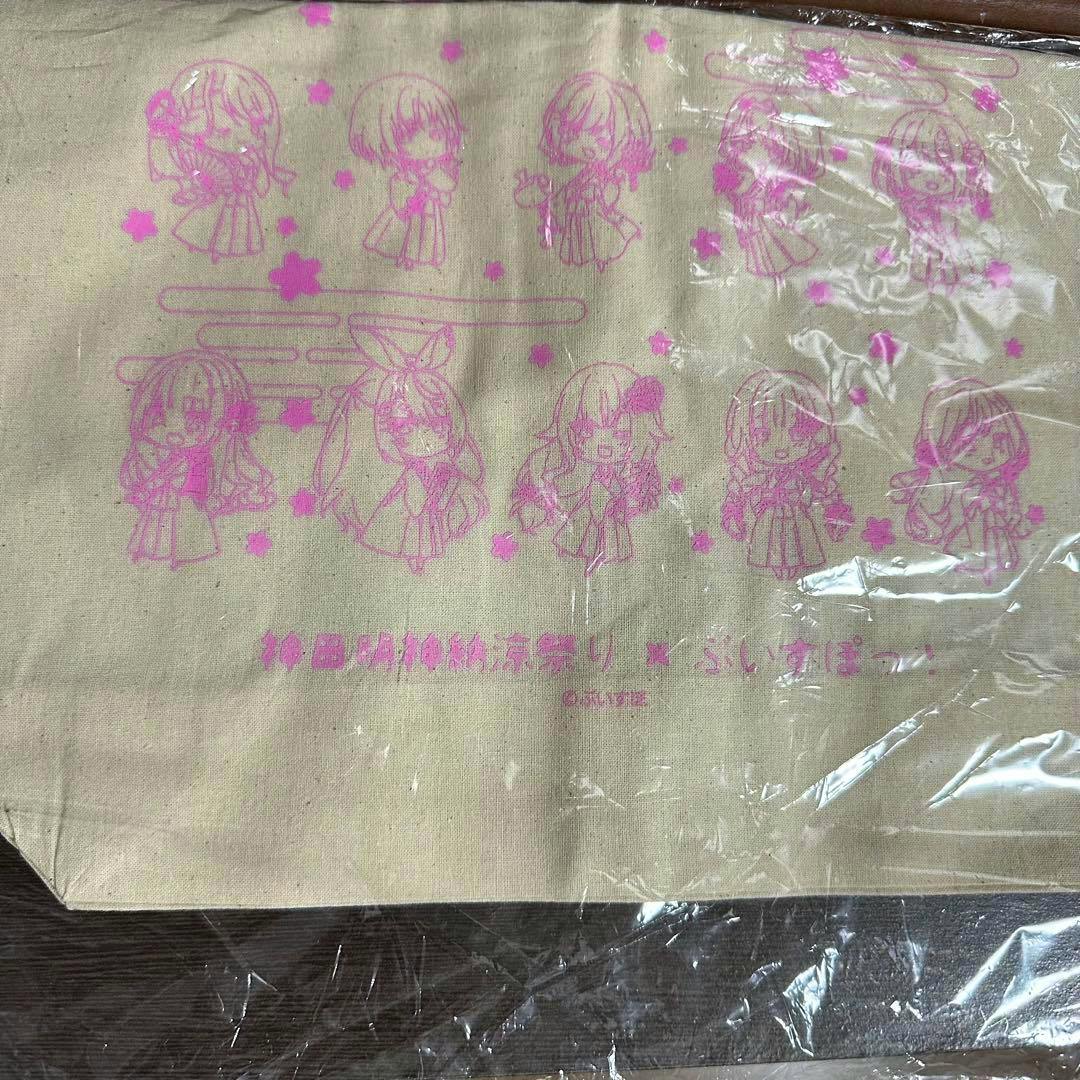 Canvas tote bag showing pink chibi character print on natural canvas, photographed flat with plastic wrap glare.