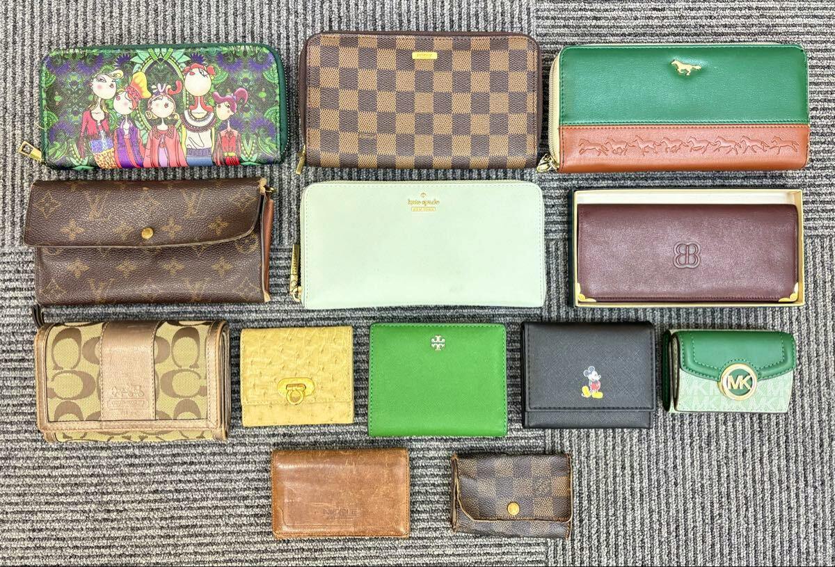 Thirteen assorted wallets and key cases arranged in rows on a gray carpet, shown as a set.