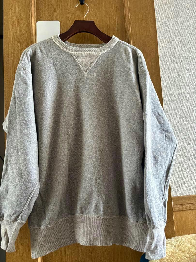 Gray men's sweatshirt (size 44) hanging on a wooden hanger against a wooden door.