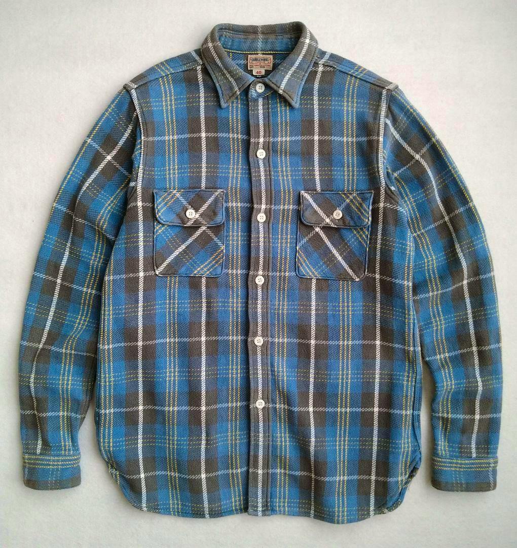 Blue and gray checked flannel men's button-up shirt laid flat showing front pockets and buttons.