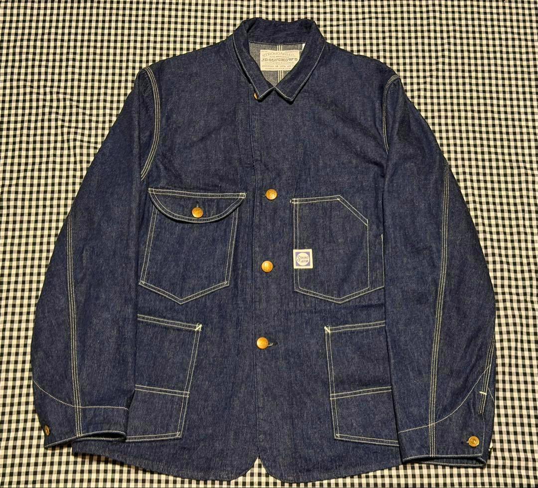 Denim coverall jacket laid flat showing the front with pockets and brass buttons, size 44.