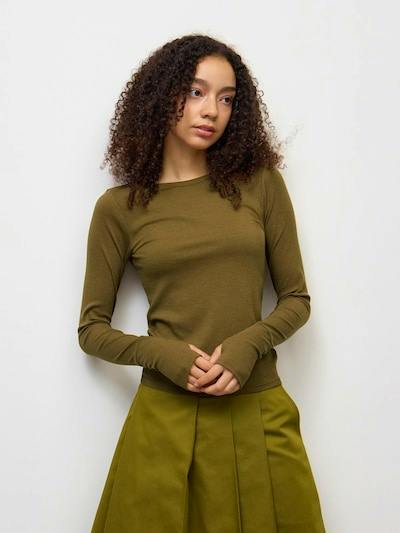 Model wearing an olive-green turtleneck sweater shown from the waist up.