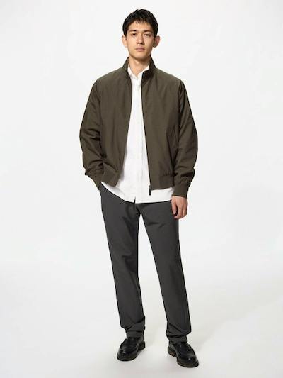 Male model standing against a white background wearing the men's nylon pants in a dark gray color, paired with a white shirt and jacket.