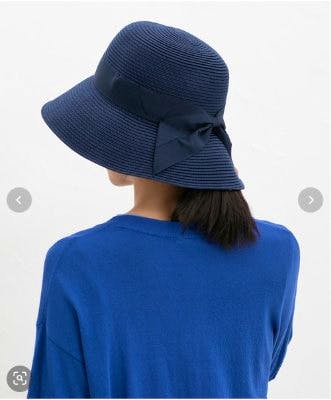 Back view of a navy wide-brim hat with a ribbon, worn by a model in a blue top.