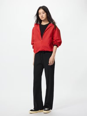 A model wearing the listed women's rib knit pants in black paired with a red jacket on a white background.