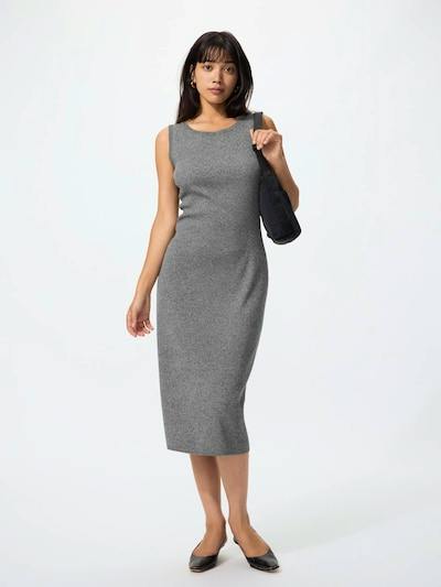 A model wearing a sleeveless grey rib-knit midi dress and holding a black shoulder bag.