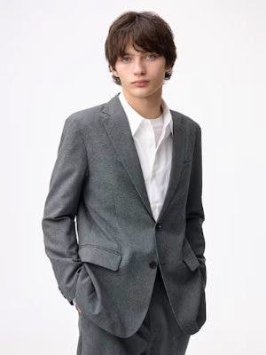 A model wearing a grey tailored jacket over a white shirt, shown from the front.