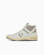 Side view of a light-colored leather high-top sneaker with a star emblem and textured sole.