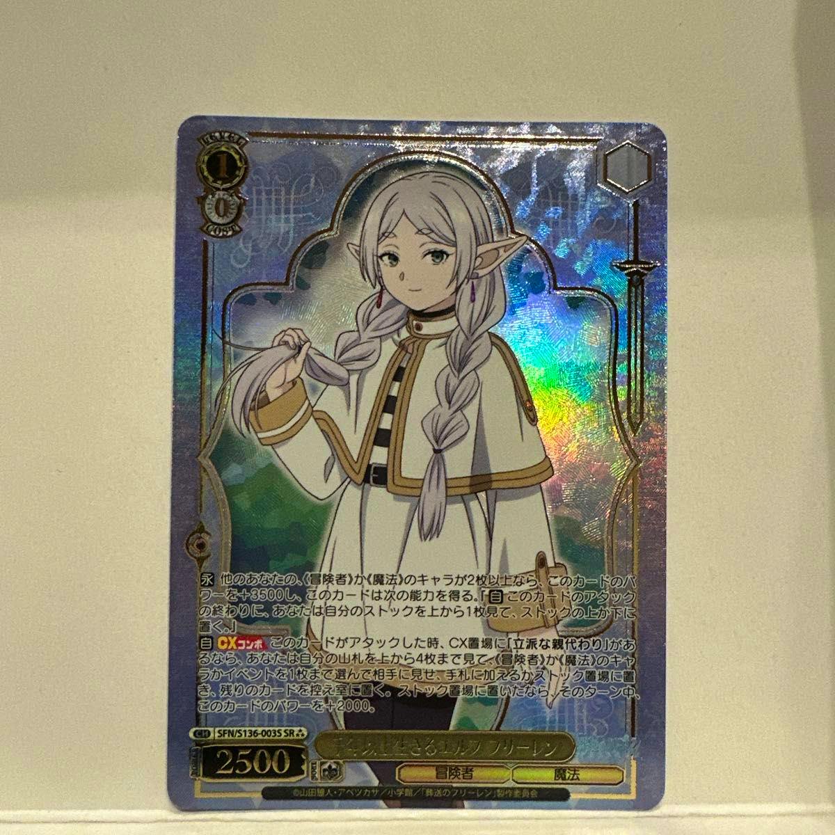 Photo of the front of a holographic Weiss Schwarz trading card showing the character フリーレン in white clothing with braided hair and Japanese text.