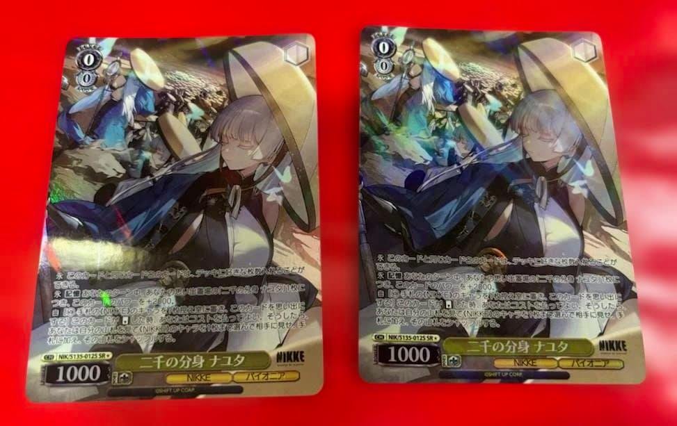 Two Weiss Schwarz (WS) NIKKE SR trading cards featuring the character NAYUTA shown side by side on a red background.