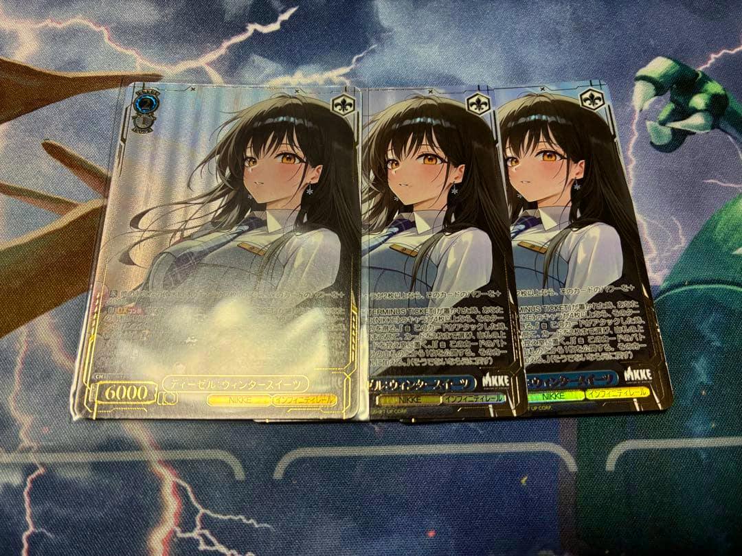 Front-facing photo of three Weiss Schwarz trading cards (ヴァイス/勝利の女神：NIKKE SR ディーゼル：ウィンタースイーツ) laid side by side showing the character artwork.