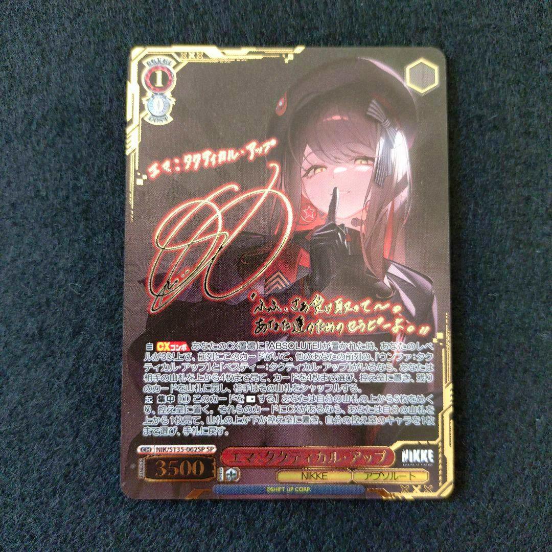 Front of a Weiss Schwarz trading card (NIKKE Vol.2 エマ SP) showing the illustrated character, a gold foil autograph, and Japanese text on a dark background.