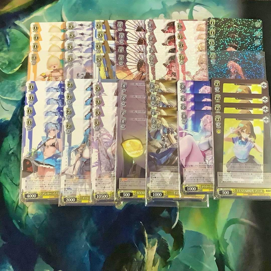 Photo of multiple Weiss Schwarz trading cards laid out in rows showing the fronts and artwork of the cards.