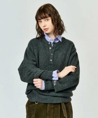Model wearing a dark brushed henley-neck knit sweater with a buttoned placket over a collared shirt.