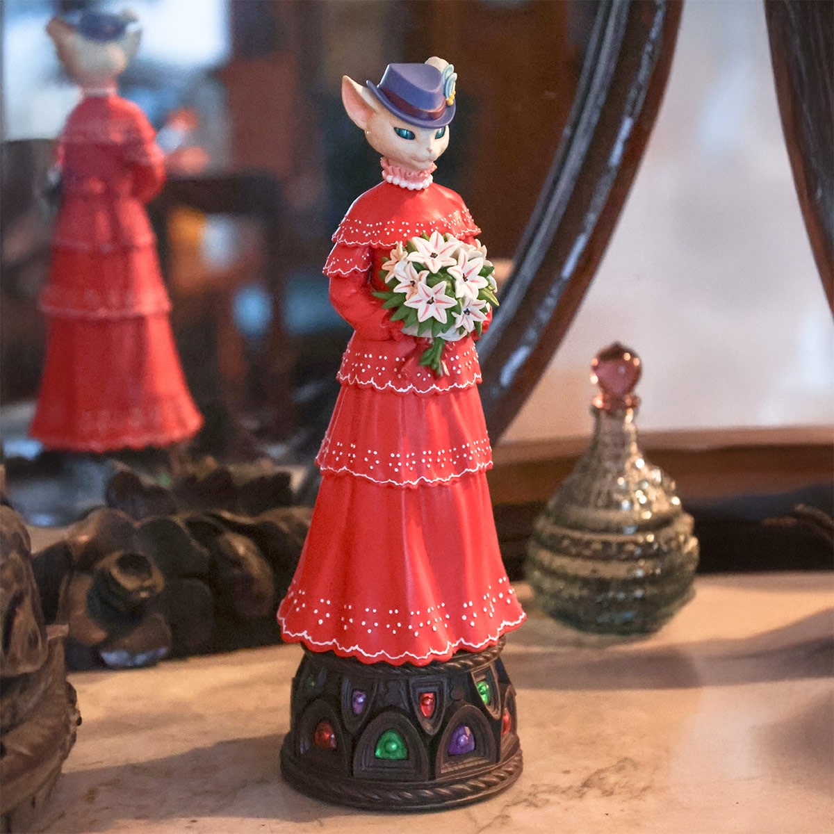Close-up of the Louise music box: a cat figure in a red dress holding a bouquet on a decorative base.