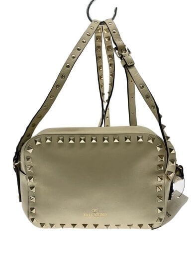Front view of a white cow-leather shoulder bag with pyramid studs and an adjustable strap.