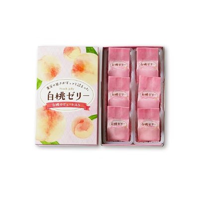 Open box showing individually wrapped white peach (peach) jellies and a peach-illustrated box lid with Japanese label.