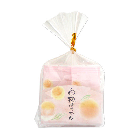 A clear plastic bag containing individually wrapped 白桃ようかん (white-peach yokan) with peach illustrations on the wrappers.