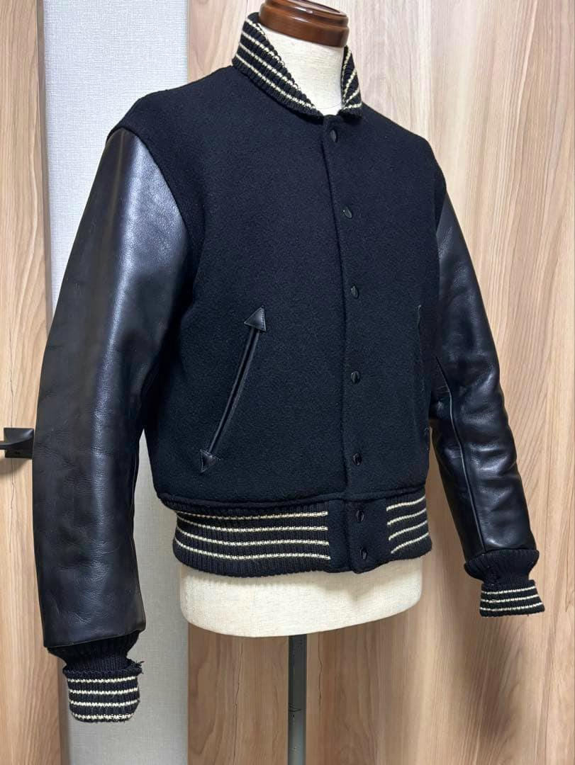 Black Whitesville sleeve-leather stadium jacket (size 38) displayed on a mannequin from a front-left angle.