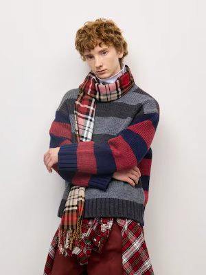 Model wearing a wide-sleeve striped sweater in gray, navy, and red.