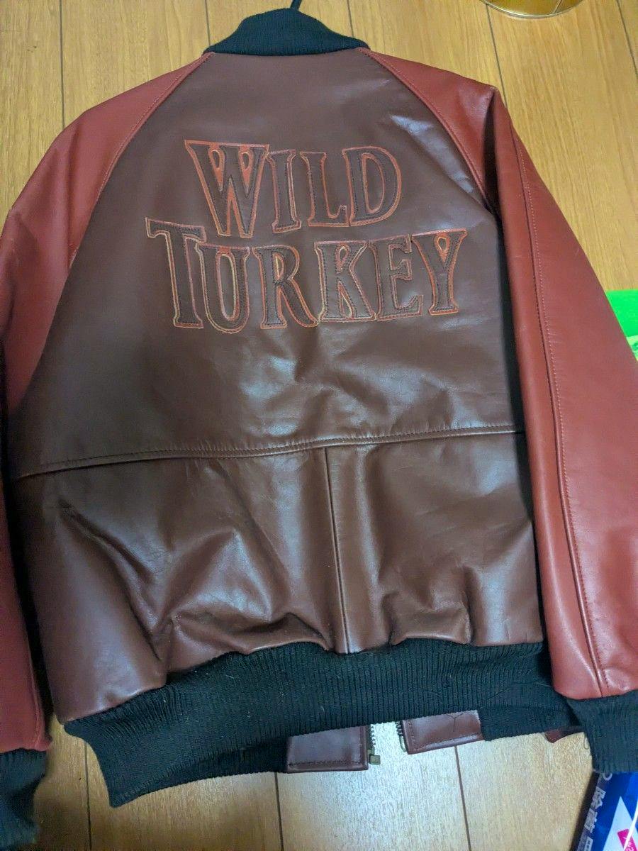 Back of a men's synthetic leather jacket showing "WILD TURKEY" embroidered on the back with red sleeves and a black ribbed waistband.