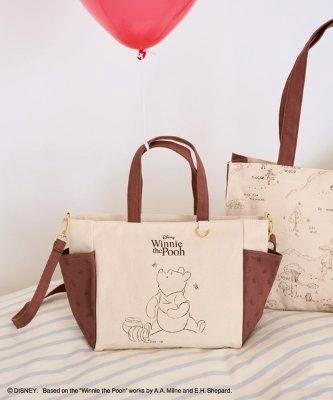 Cream-colored Winnie the Pooh 2-way tote bag with brown handles and side panels and a printed Pooh illustration on the front.