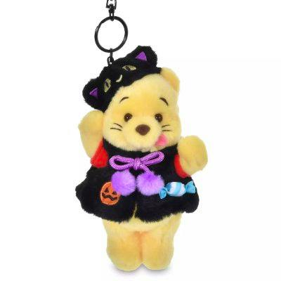 Winnie the Pooh plush keychain wearing a black cat Halloween outfit and holding candy.