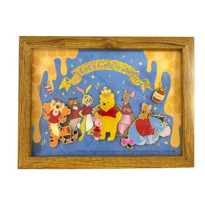 A wooden frame displaying Winnie the Pooh and friends pins arranged on a blue and yellow honeycomb-style background.