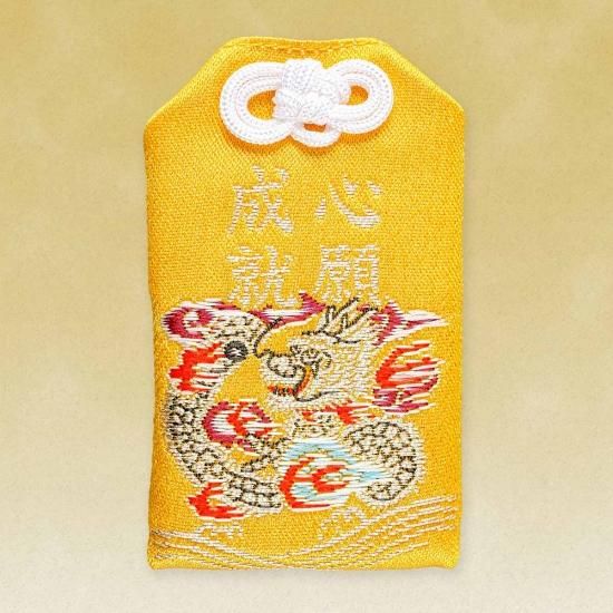 Yellow embroidered cloth amulet (omamori) with a dragon motif and embroidered characters.