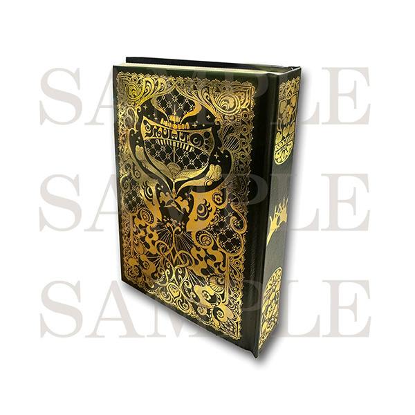 A black hard-cover notebook shown standing at an angle with an ornate gold-foil decorative cover design.