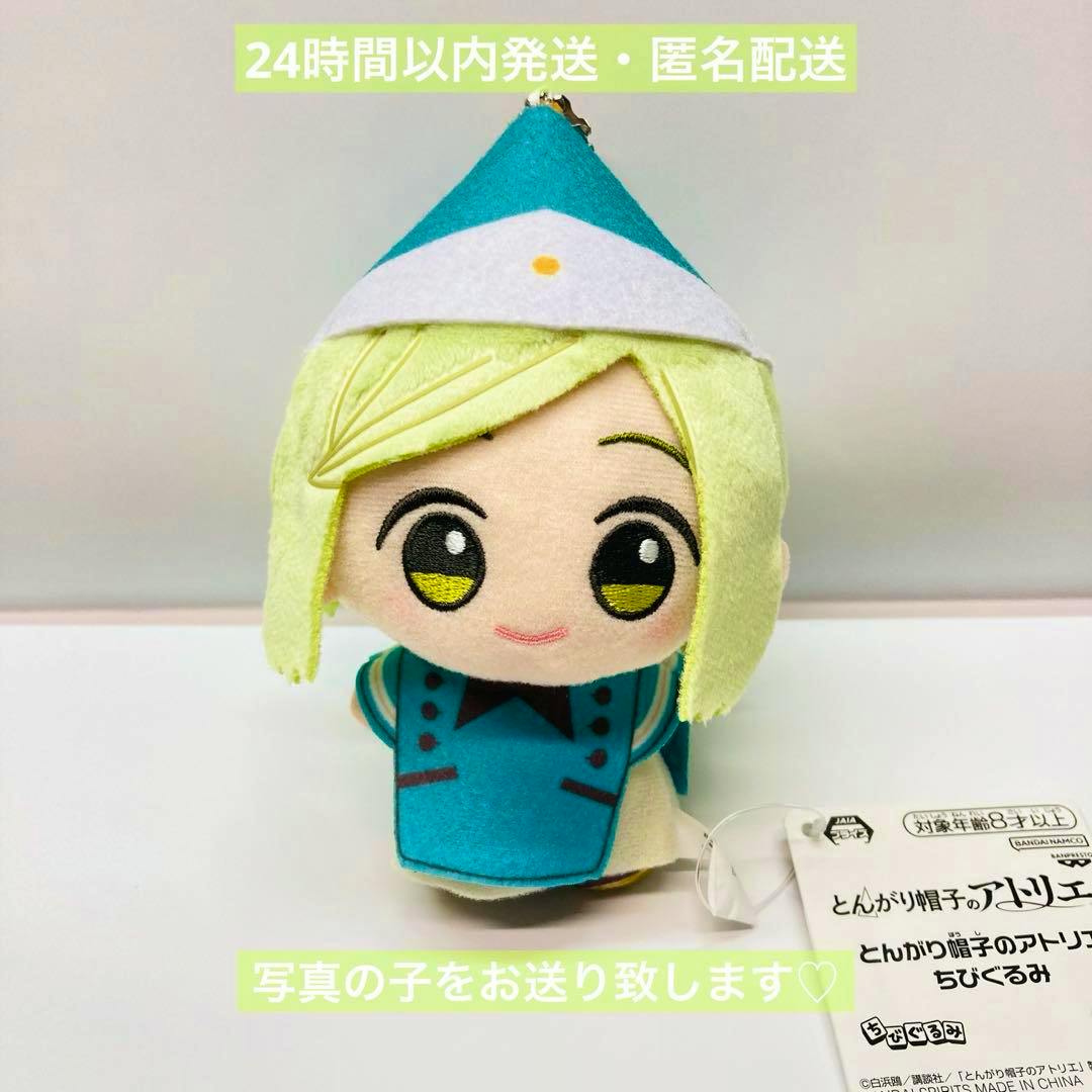 Front view of the とんがり帽子のアトリエ ちびぐるみ ココ plush toy showing its face, hat, outfit, and attached tag on a white surface.