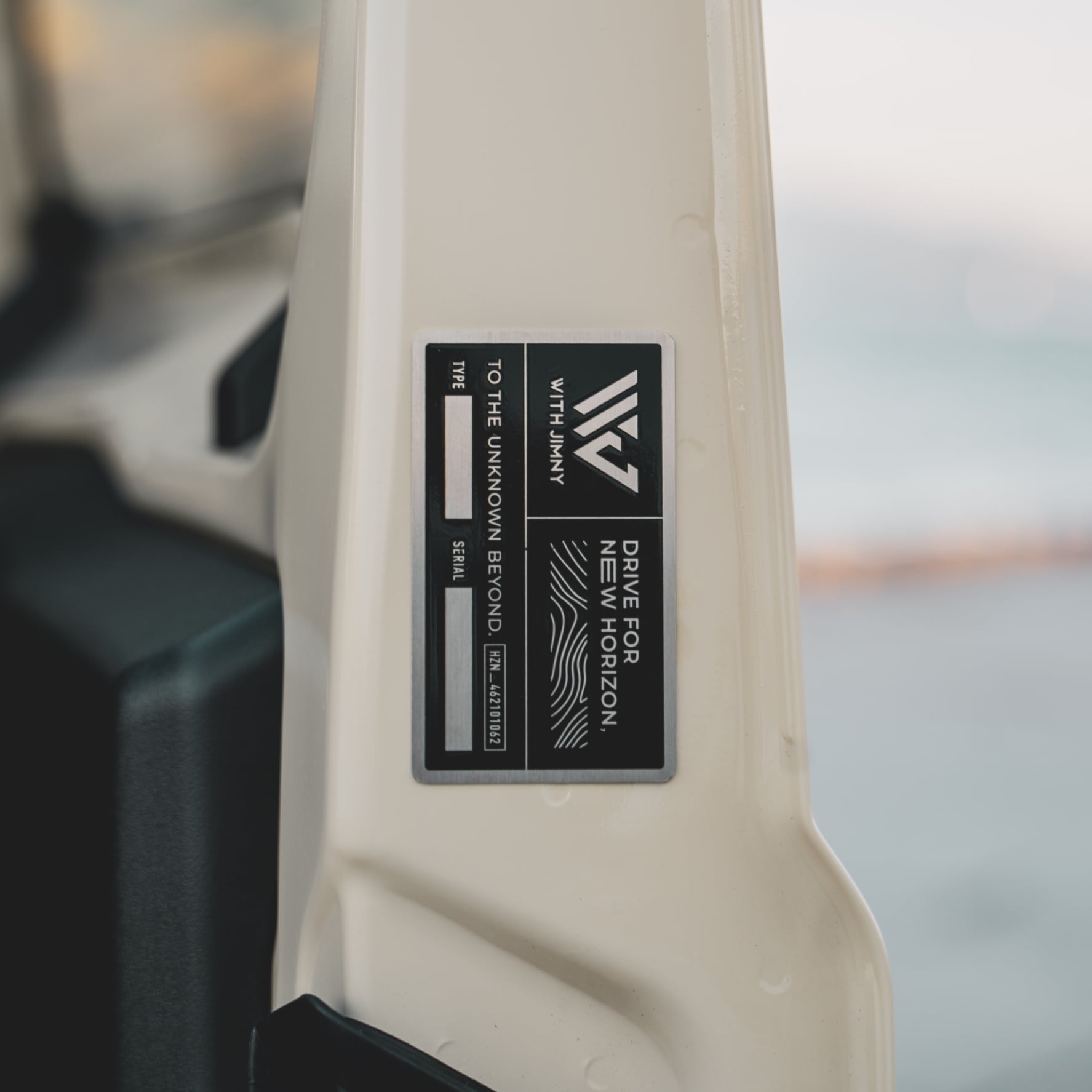 Close-up photo of the metal WITHJIMNY custom nameplate attached to a vehicle interior pillar.