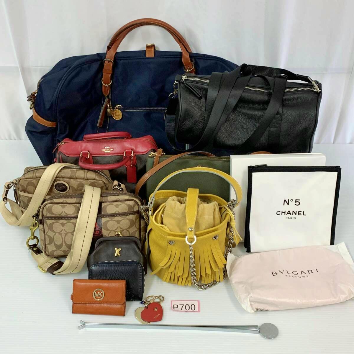 Multiple women's bags and small accessories, including canvas and leather styles, arranged on a white surface.