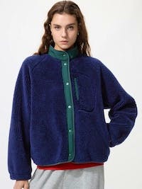 Woman wearing a navy blue boa fleece combination jacket shown against a white background.