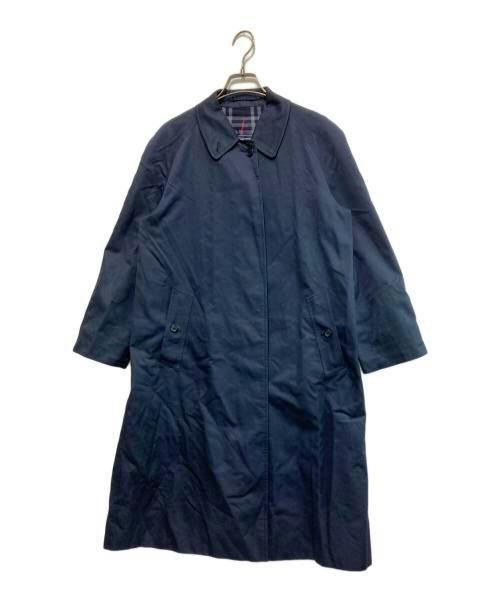 Navy women's trench coat (cotton) with checked lining visible at the collar, hanging on a hanger against a white background.
