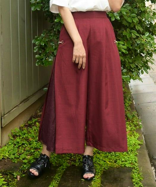 Model wearing burgundy women's wide pants with lace side panels visible through side slits.