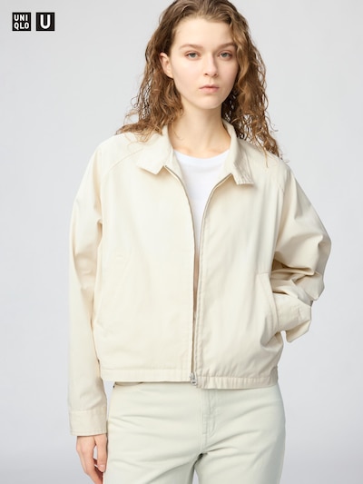 Woman wearing a light-colored short cotton-blend blouson jacket with a front zip.