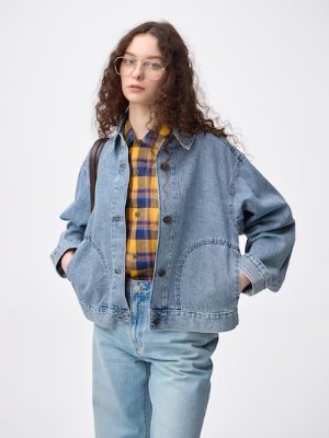 Woman wearing a light-blue denim jacket over a plaid shirt.