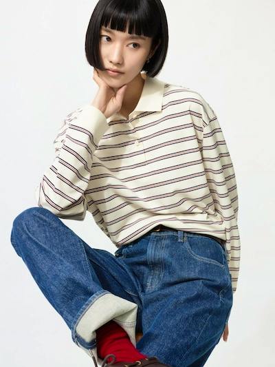 Seated model wearing the striped long-sleeve polo shirt with jeans.