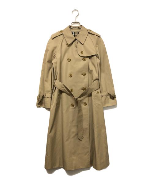 Beige women's cotton trench coat hanging on a hanger against a white background.