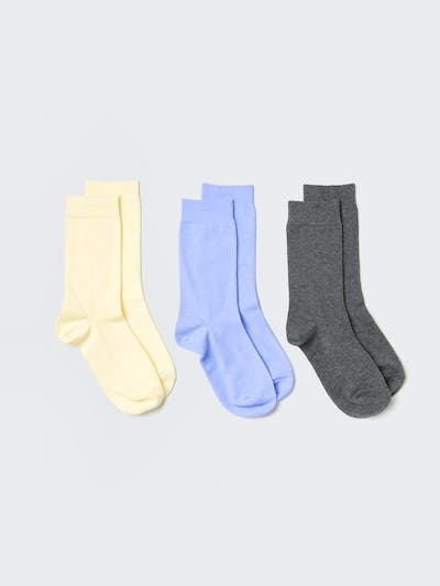Three pairs of women's very-short cotton sports socks in pale yellow, light blue, and dark gray laid flat on a light background.