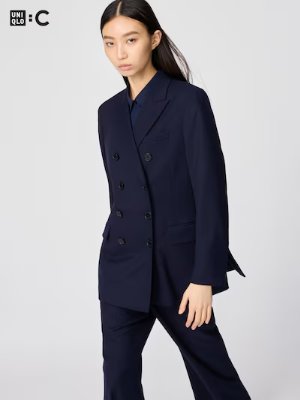 A woman modeling a navy double-breasted women's polyester tailored jacket.