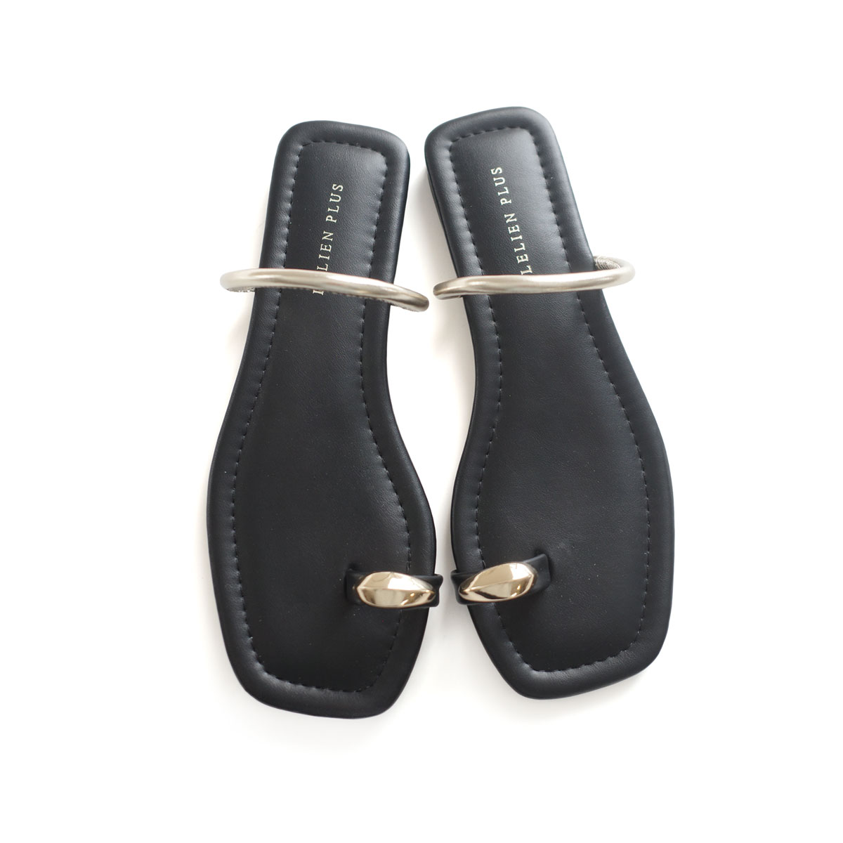 Top-down view of a pair of black synthetic-leather women's flat sandals with square toes and metallic toe and ankle rings on a white background.