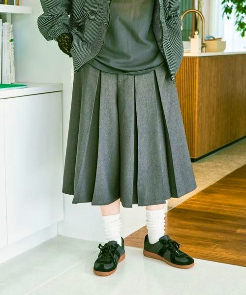 A model wearing gray front-pleated women's half pants shown from the waist to the ankles.