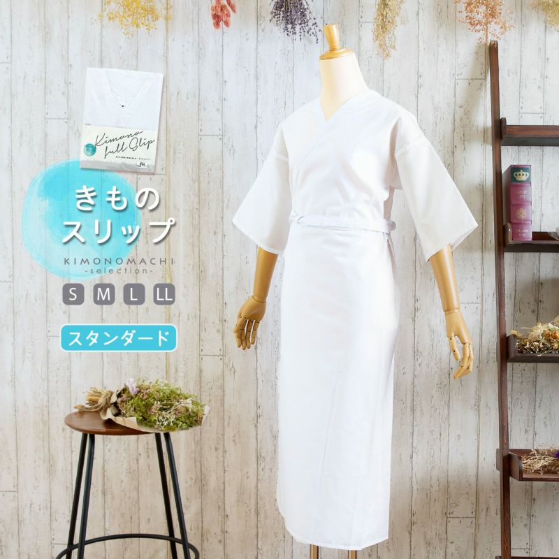 White kimono-style slip (undergarment) displayed on a mannequin against a light wooden background beside a small table and shelving.