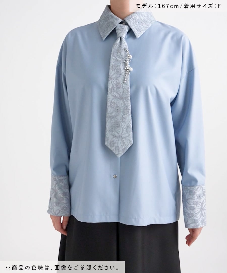 Front view of a women's polyester necktie shirt in light blue, showing patterned collar and cuffs and an attached decorative tie with pearl accents, worn by a model.