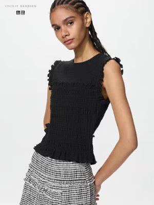 Model wearing a black sleeveless shirred top.