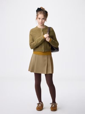 Model wearing the side-pleated skirt paired with a cardigan and tights.