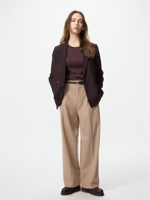 A model wearing beige wide tuck women's pants styled with a dark blazer and top.